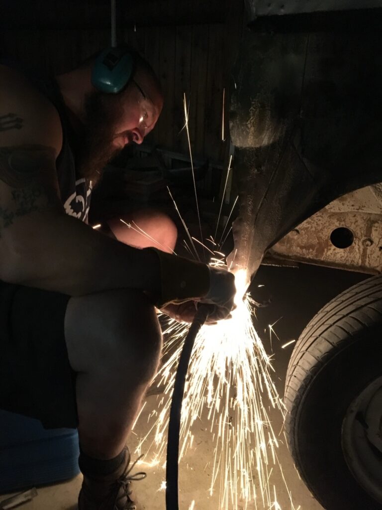 Hands-on metalwork at Black Cloud Customs, with sparks flying beside a vehicle