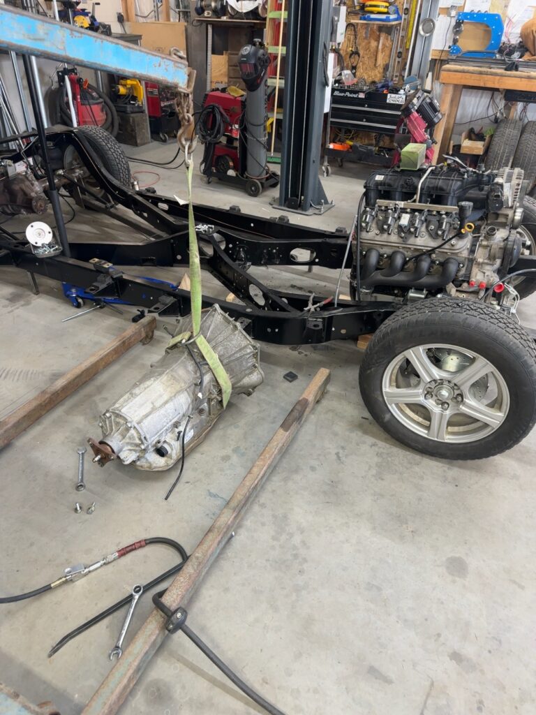 Ole Nasty chassis with engine installed and transmission being positioned in the workshop